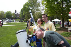 Blair advertises for a campus sponsor while a member of the public takes a look through Jacob's telescope.