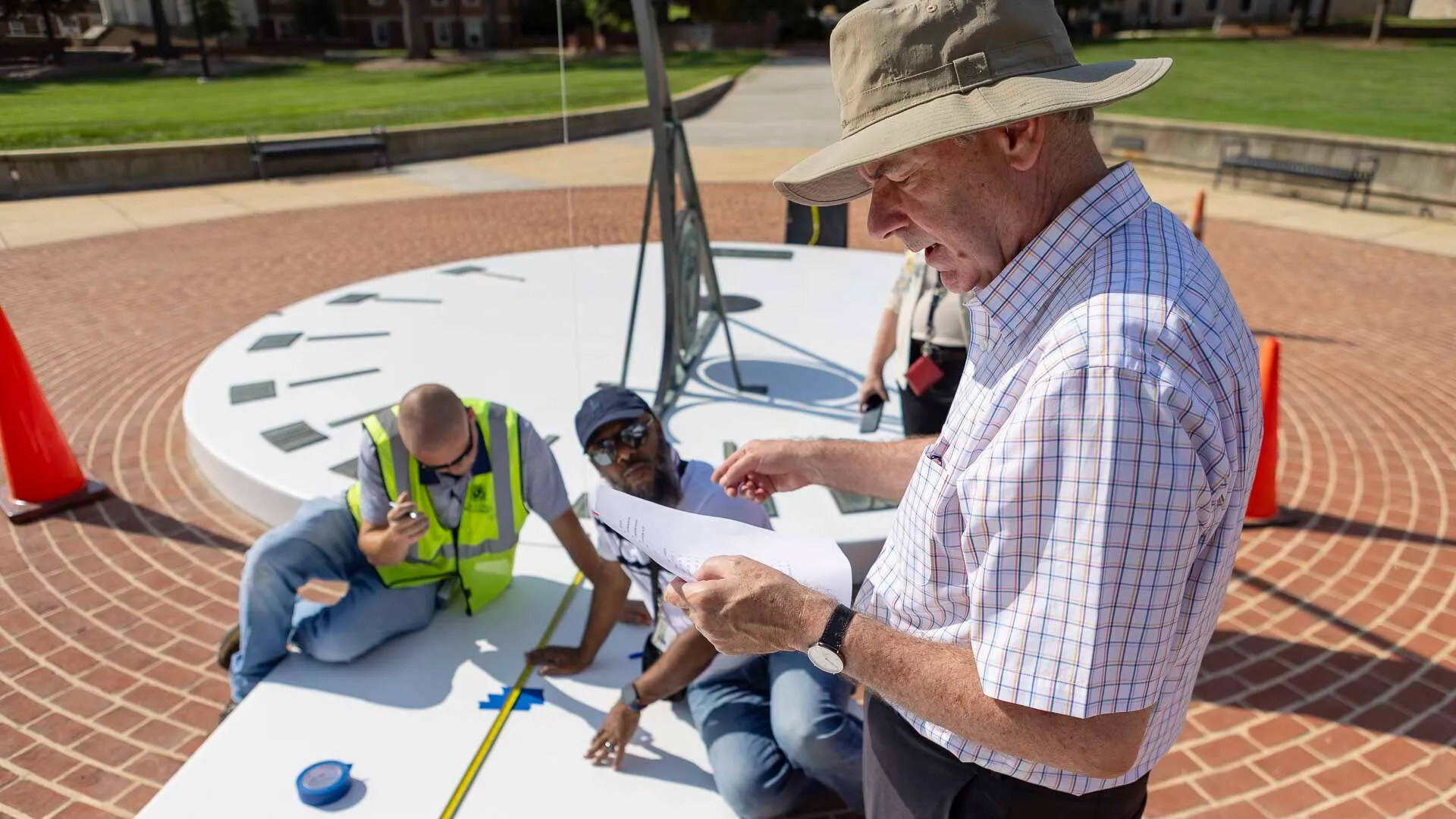 Professor Andrew Harris works with the facilities team to correct the placement of the month markers on the McKeldin Mall sundial on August 18, 2026.Photo by Dylan Singleton/University of Maryland