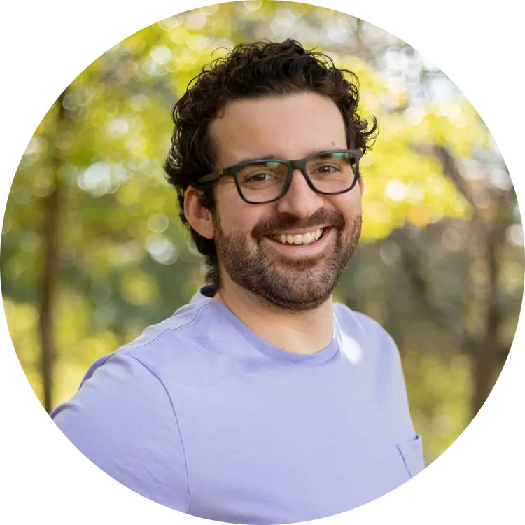 Mike Greklek-McKeon; dark hair, beard and glasses posing outside