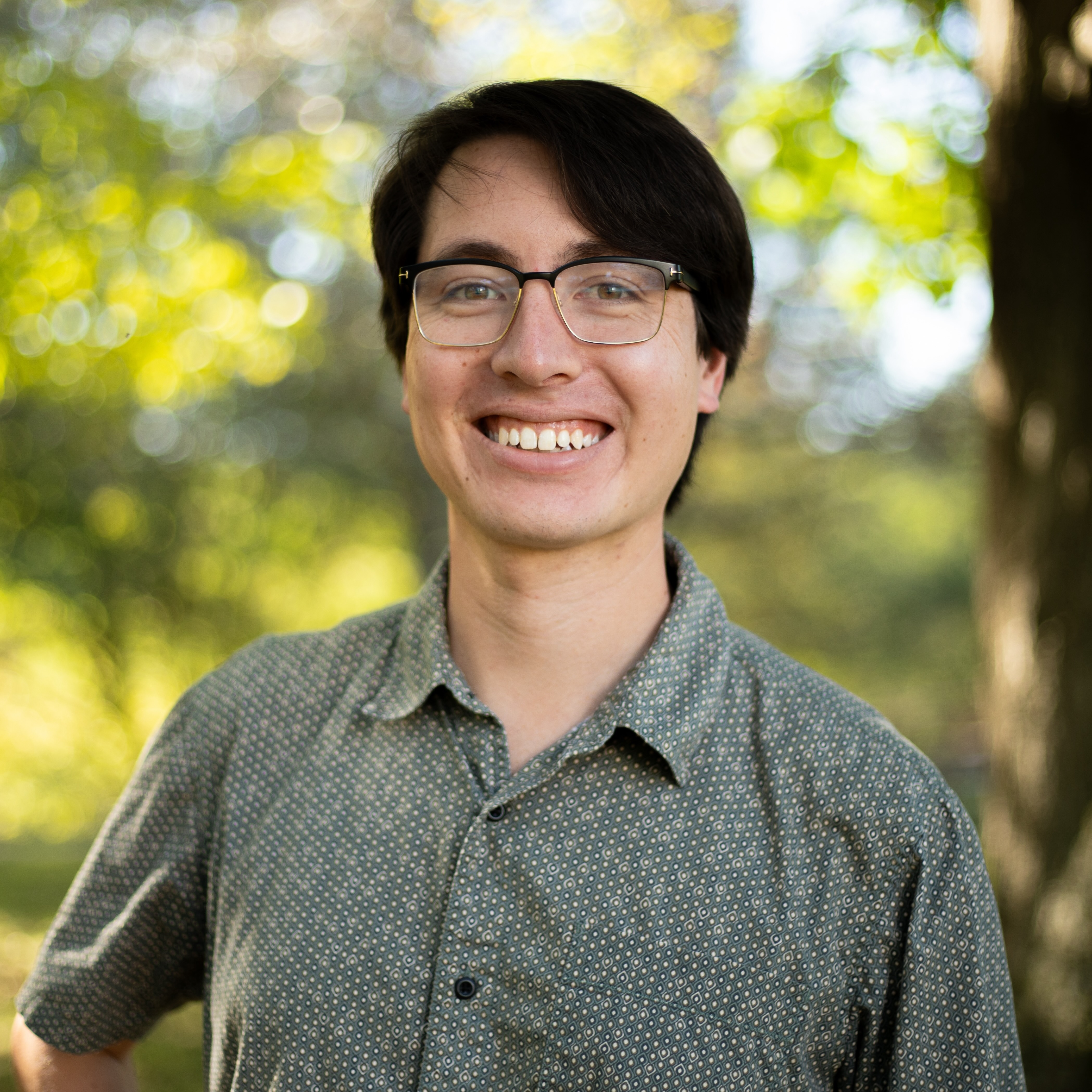 Man with black hair wearing glasses outside