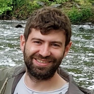 bearded man in front of a river