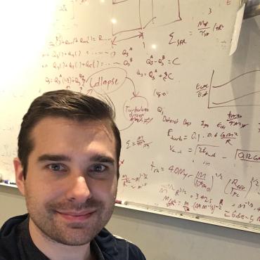 Mike Grudic; man, short hair in front of whiteboard filled with equations