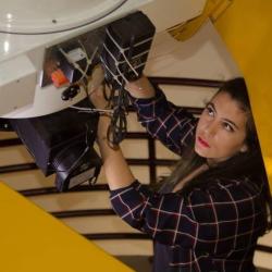woman inspecting camera end of large telescope