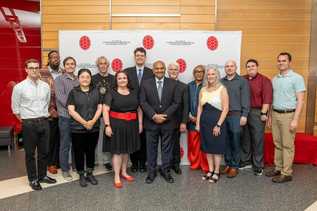 CMNS employee award recipients standing and smiling in front of a branded backdrop