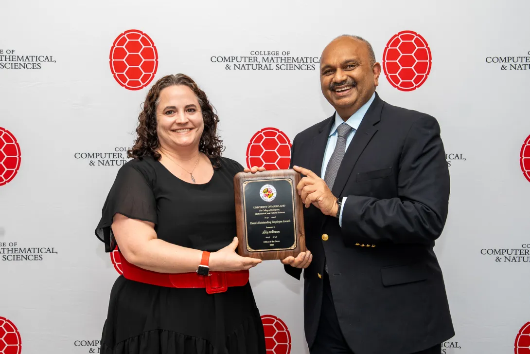 Abby Robinson and Amitabh Varshney holding plaque in front of CMNS branded backdrop