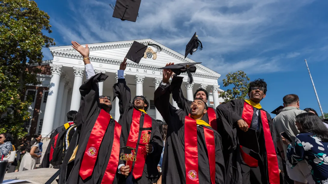 A group of master's degree students tossing their caps in the air.
